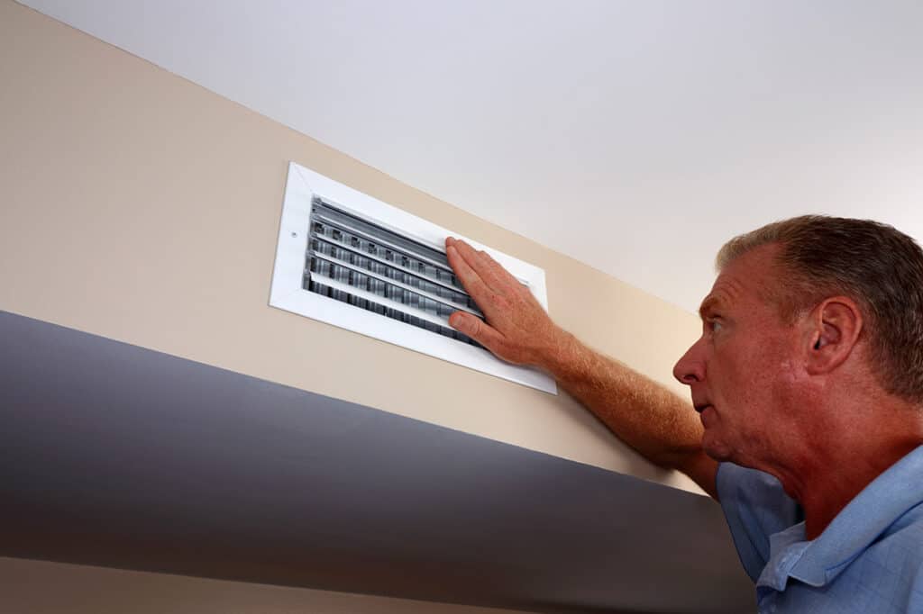 Man checking air coming out of ac vent